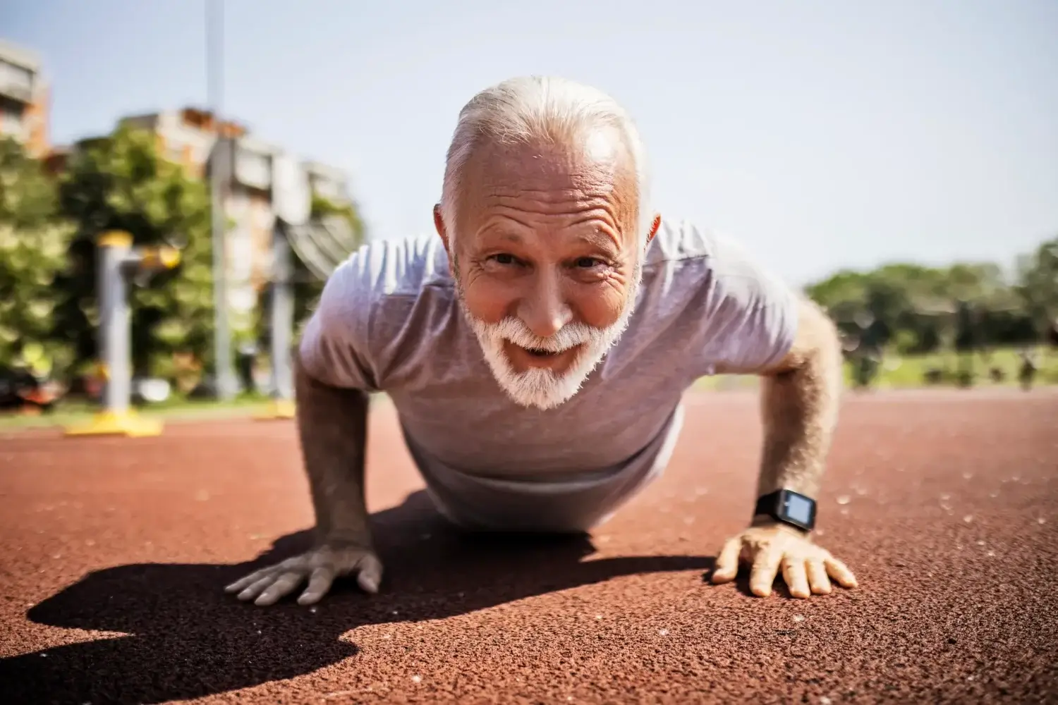 Older man doing push ups outside while smiling